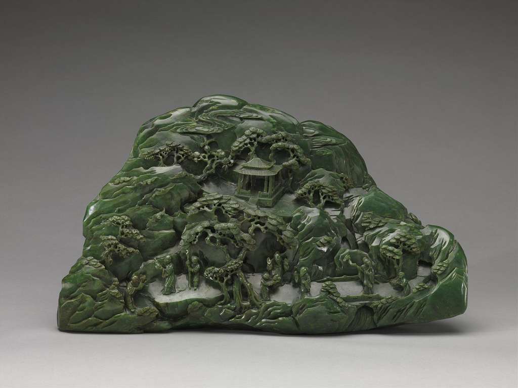 A detailed mural on a larger green jade stone. This piece shows a intricately carved scene of a temple, monks, and trees. 