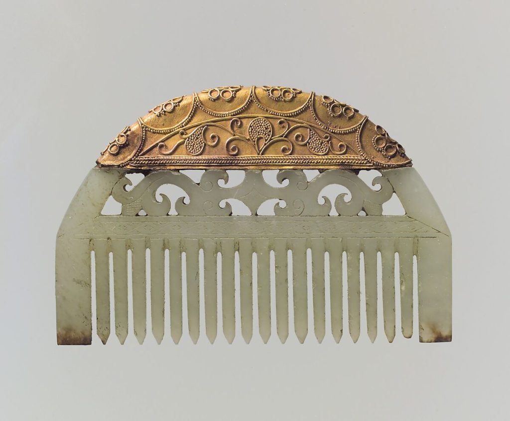 A simple comb. The prongs are made of carved white jade and the piece is topped with intricate gold patterns.
