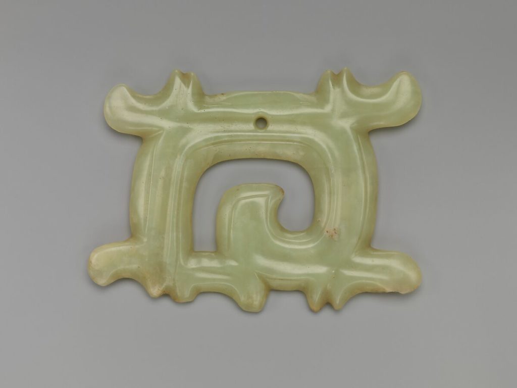 A simple carving of white / light green jade. There is a small hole in the top suggesting it was a pendant worn over 4000 years ago.